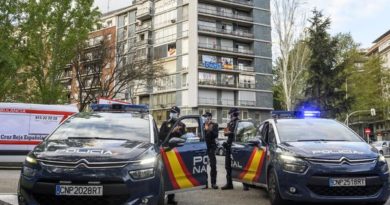Fotografia de dos coches de la policia nacional aparcados y tres agentes a su lado