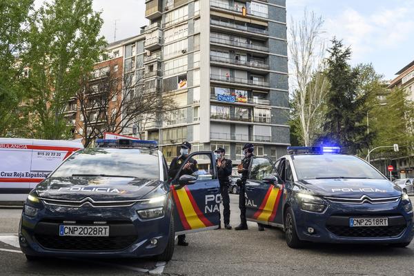 Fotografia de dos coches de la policia nacional aparcados y tres agentes a su lado